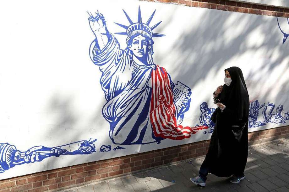 Una mujer pasa junto a un mural pintado en las paredes exteriores de la ex embajada de Estados Unidos en Teherán, capital de Irán.