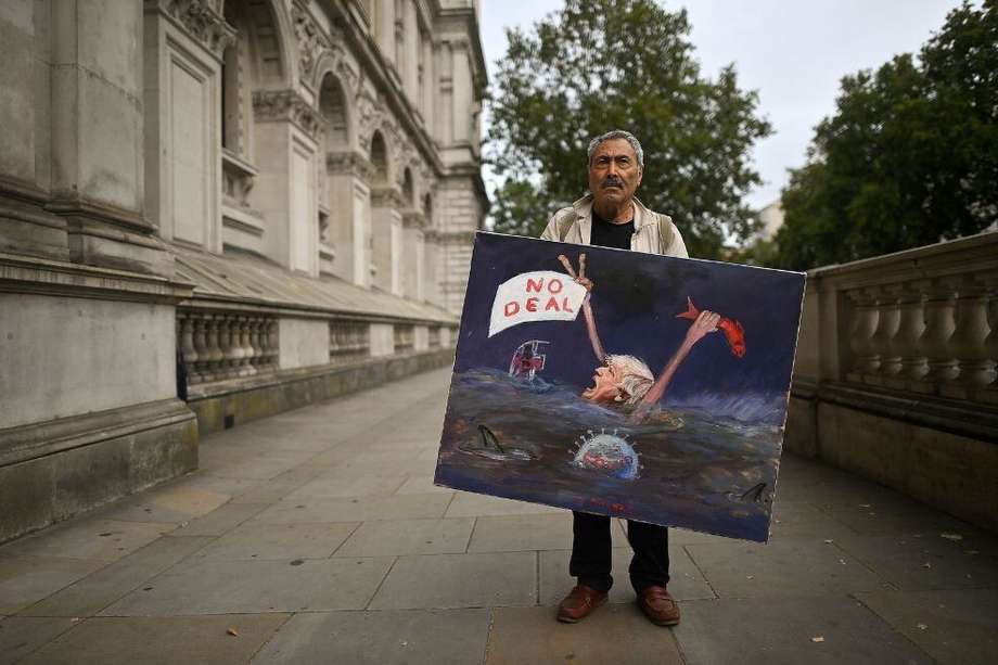 El artista Kaya Mar junto a una pintura que representa al primer ministro británico Boris Johnson ahogándose, mientras posa frente a la entrada de Downing Street en el centro de Londres.