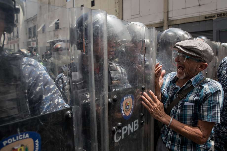 Miembros de distintos sindicatos de profesores, jubilados y demás trabajadores del sector educativo increpan hoy a policías durante una manifestación por mejoras salariales, en Caracas.