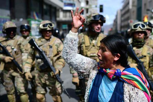Una mujer indígena boliviana, partidaria del ex presidente boliviano Evo Morales, hace un gesto frente a los soldados durante una protesta contra el gobierno interino en La Paz el 15 de noviembre de 2019. / AFP