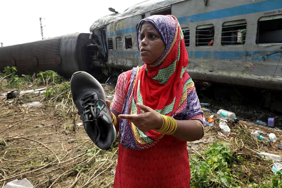 Una mujer muestra un zapato de su hijo desaparecido, encontrado cerca de un compartimento del tren accidentado en Odisha Balasore, India.