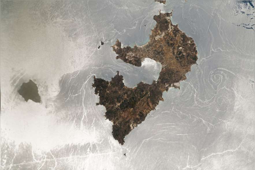 Otro astronauta de la ISS captó una impresionante fotografía de un "destello solar" que transformó la superficie del mar en un espejo plateado arremolinado alrededor de un par de islas griegas.
La mayor masa de tierra en el centro de la foto es Milos, una isla volcánica griega de 151 kilómetros cuadrados, y su diminuta y deshabitada compañera al oeste es Antimilos, de unos 8 kilómetros cuadrados.