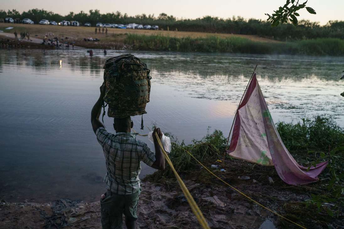 A Haitian man crosses the Rio Grande towards the US after Mexican police and National Institute of Migration officials blocked the Mexican side of the border at Parque Ecologico Braulio Fernandez in Ciudad Acuna, Coahuila state, Mexico on September 23, 2021. (Photo by PAUL RATJE / AFP)