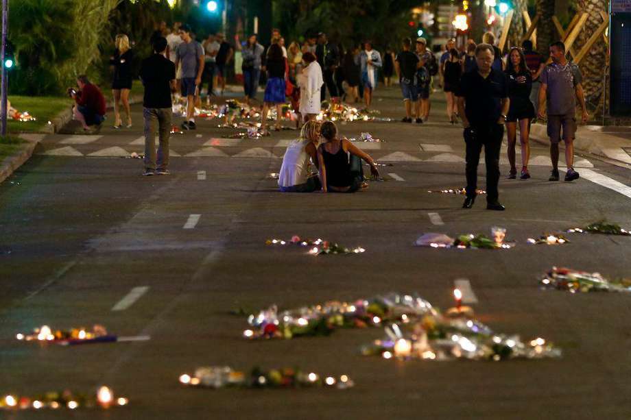 Personas caminan entre flores y velas en el 'Promenade des Anglais' donde el camión se estrelló contra la multitud durante las celebraciones del Día de la Bastilla, en Niza, Francia, el 17 de julio de 2016.