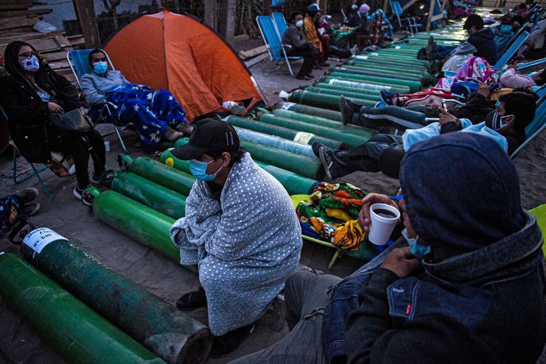 Decenas de personas forman largas filas frente a una planta ubicada en el barrio Villa El Salvador, en Lima, para poder recargar sus balones de oxígeno medicinal de forma gratuita.