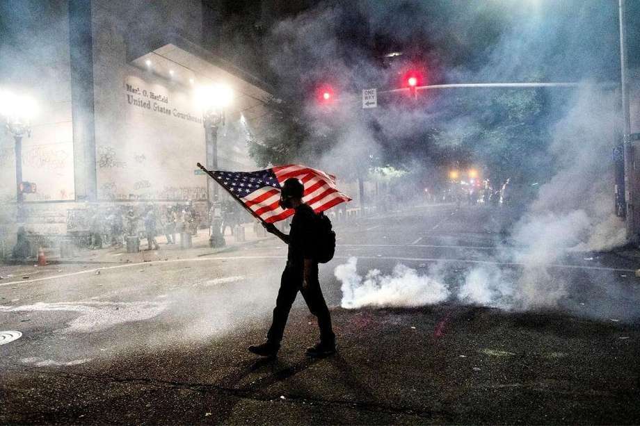 Un manifestante ondea la bandera de Estados Unidos en las protestas de Portland, Oregon.
