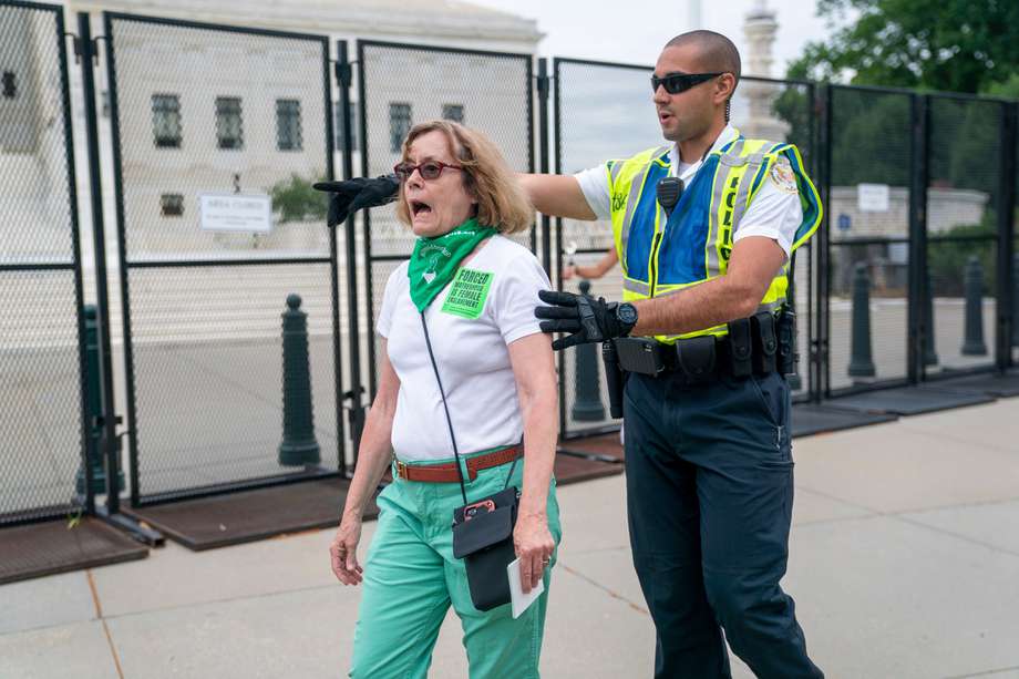 Un policía de la Corte Suprema escolta a una activista por el derecho al aborto fuera de la zona segura.