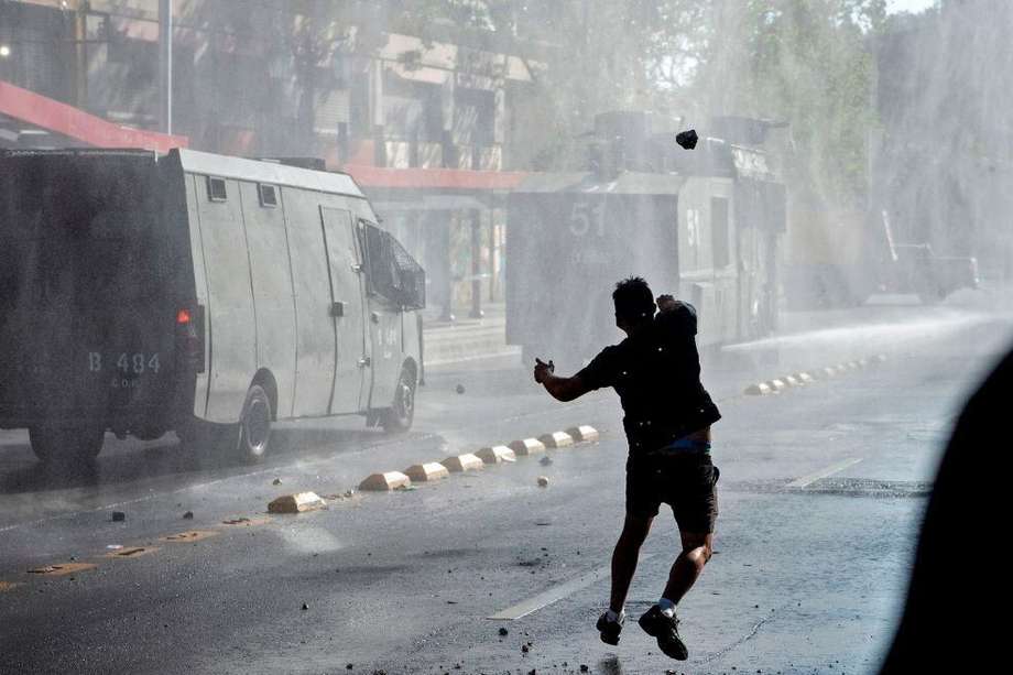 Un manifestante lanza una piedra contra un vehículo de la policía antidisturbios durante una protesta contra el gobierno del presidente chileno, Sebastián Piñera, en Santiago.
