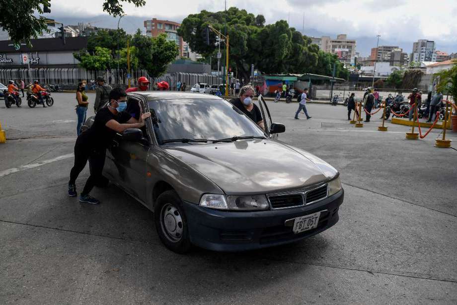 Ciudadanos venezolanos empujan un carro hasta una estación de gasolina en Caracas.