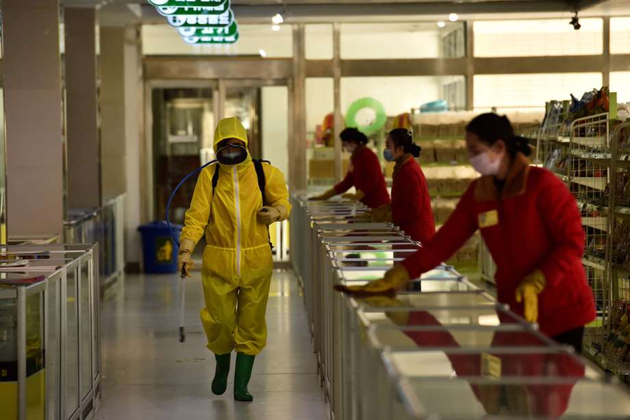 En esta foto de archivo tomada el 18 de marzo de 2022, los empleados rocían desinfectante y limpian superficies como parte de las medidas preventivas contra el coronavirus Covid-19 en los grandes almacenes infantiles de Pyongyang en Pyongyan.
