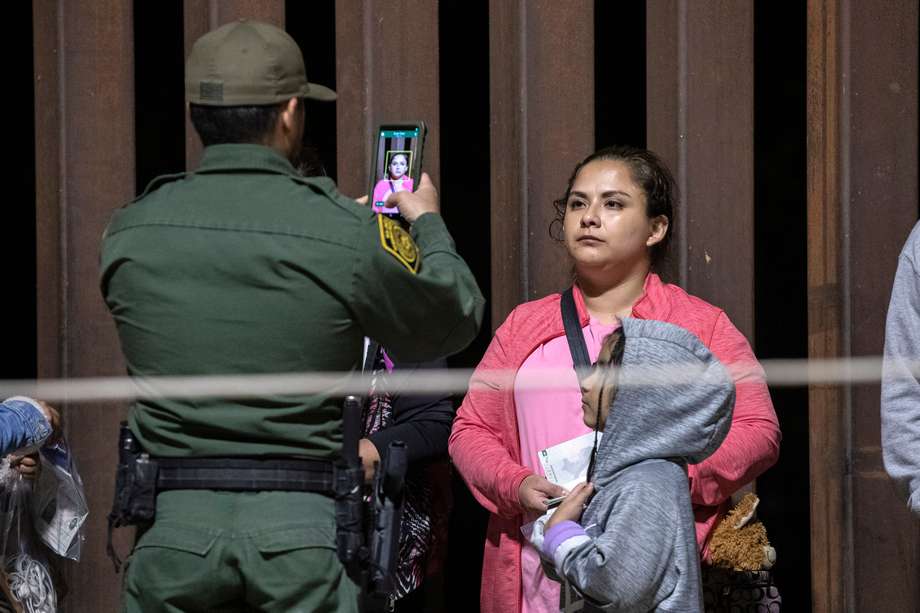 Una mujer migrante y su hija son fotografiadas por un agente de la patrulla fronteriza mientras son procesadas tras cruzar ilegalmente en EE. UU., en Yuma, Arizona.