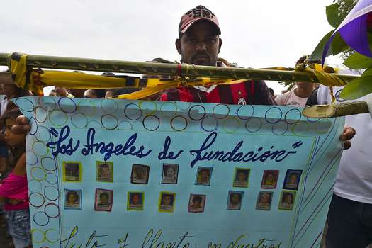 A man holds a poster with pictures of 16 of the 32 children burnt to death inside a school bus in Fundacion, department of Magdalena, Colombia, on May 19, 2014. Colombians expressed horror Monday after 32 children burnt to death when an overcrowded bus burst into flames and the driver fled the scene, pursued by a mob that stoned his house. According to a witness, the bus went up in flames as the driver, who lost two of his own children in the tragedy, refuelled it with a jerrycan. The children, aged between three and 12 years old, were returning from evangelical church services in the small northern town of Fundacion.  AFP PHOTO/Luis Acosta