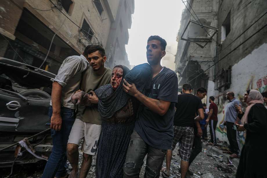 Una mujer herida recibe ayuda para alejarse del lugar de un ataque con cohetes israelíes en el campo de refugiados de Al-Shati, en el oeste de la ciudad de Gaza.
