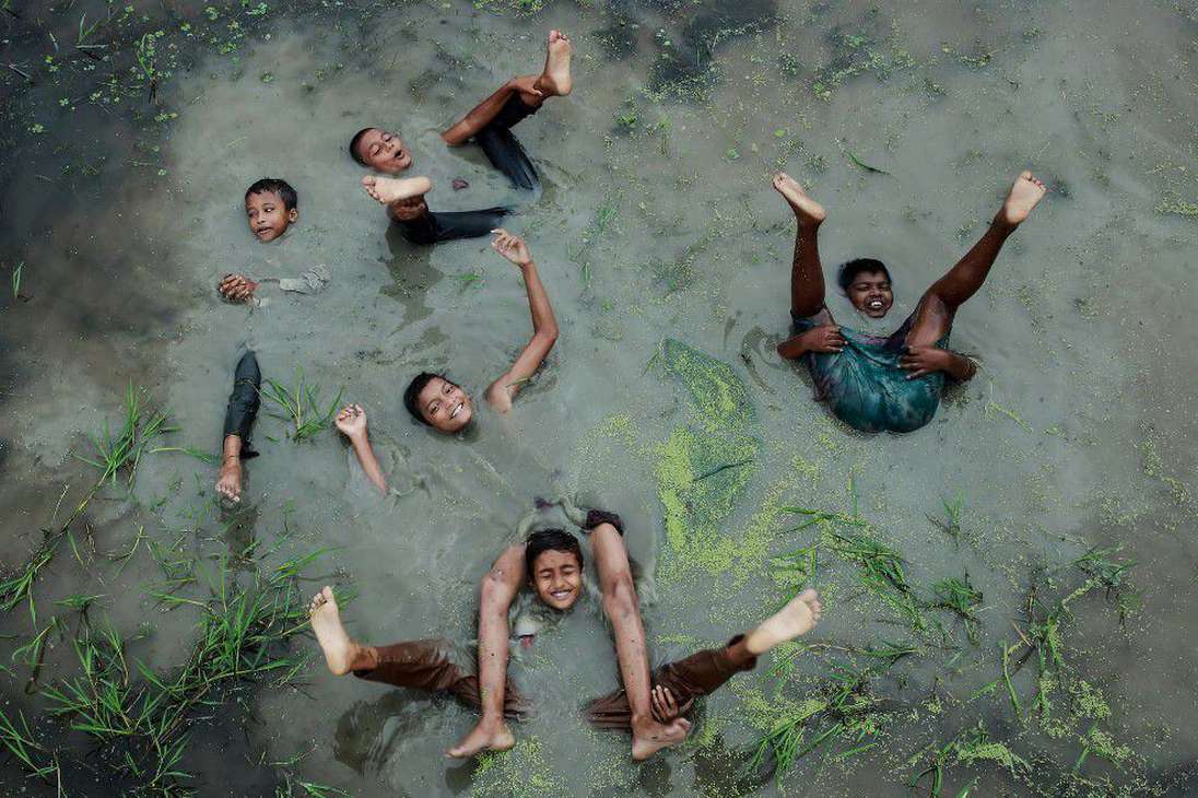 La alegría de la infancia de Muhammad Amdad Hossain muestra a unos niños de una aldea, en Bangladesh, cómo celebran y juegan en el agua durante el monzón.