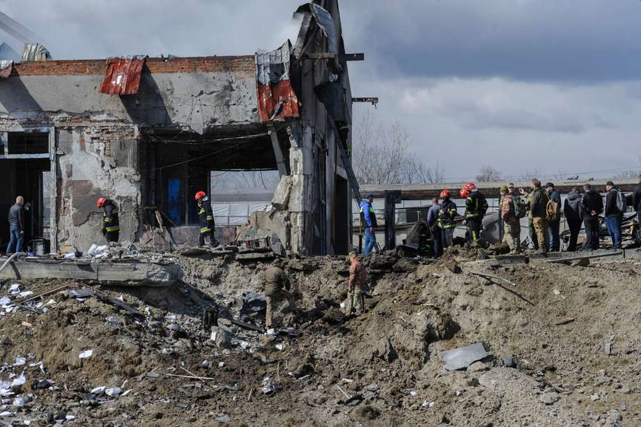 Los rescatistas ucranianos revisan el centro de servicio de automóviles dañado después del bombardeo ruso en la ciudad de Leópolis. 

