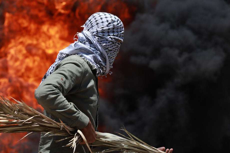 Un manifestante palestino trata de huir de una explosión provocada por una granada de humo, durante una manifestación contra la anexión de partes de Cisjordania por parte de Israel. / EFE