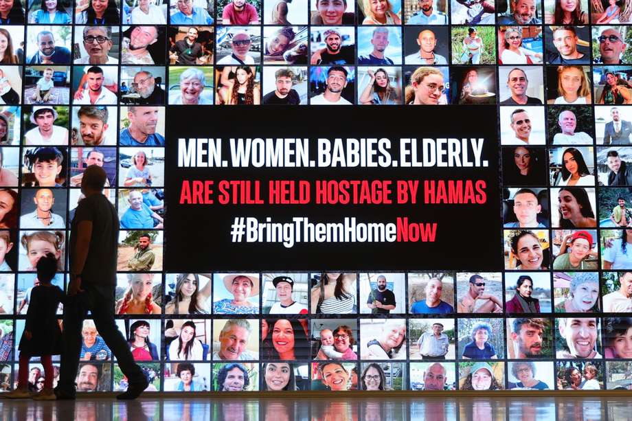 En Tel Aviv, la gente pasa junto a un cartel que muestra fotografías de personas secuestradas por Hamás.