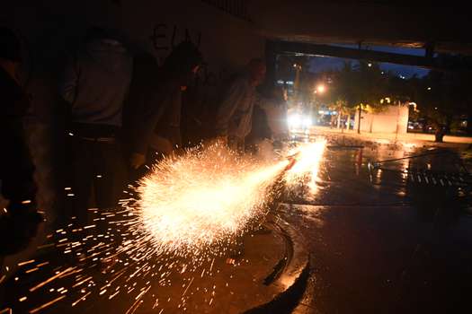 En la Universidad Nacional, unos manifestantes lanzan un artefacto explosivo a la policía durante protestas.