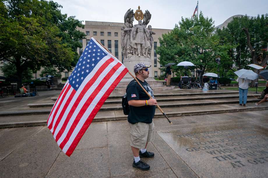 Un hombre lleva una bandera estadounidense fuera del tribunal federal de DC en Washington, DC, EE. UU. 