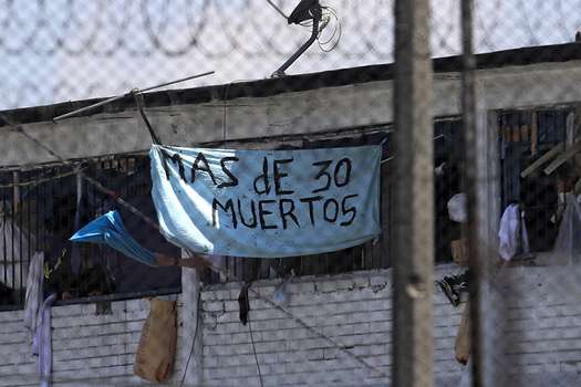 Un grupo de reclusos sostiene una pancarta anunciando el número de muertos. / AFP