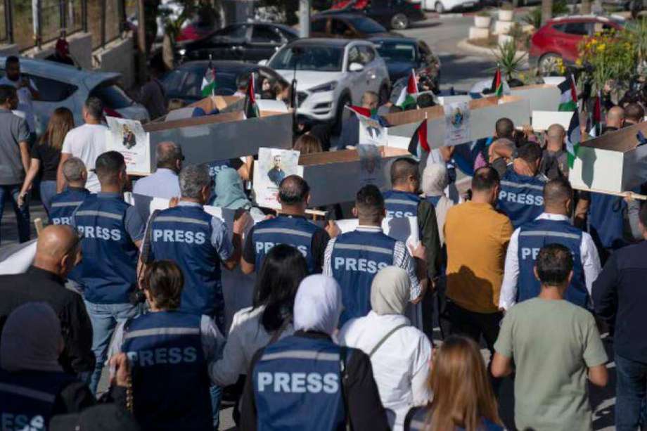 Periodistas palestinos llevan ataúdes simulados de periodistas palestinos que fueron asesinados durante la actual guerra en Gaza durante un funeral simbólico hacia una oficina de las Naciones Unidas, en la ciudad cisjordana de Ramala, el martes 7 de noviembre de 2023.