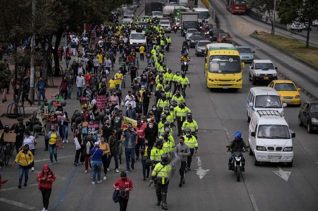 Un grupo de manifestantes marcha sobre un carril de la vía acompañados de policías.