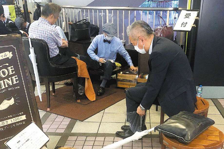Un lustrador de zapatos en plena jornada laboral en el barrio de Hibiya, en el centro de Tokio. Les da bolsas de plástico a los clientes para no mancharles las medias.