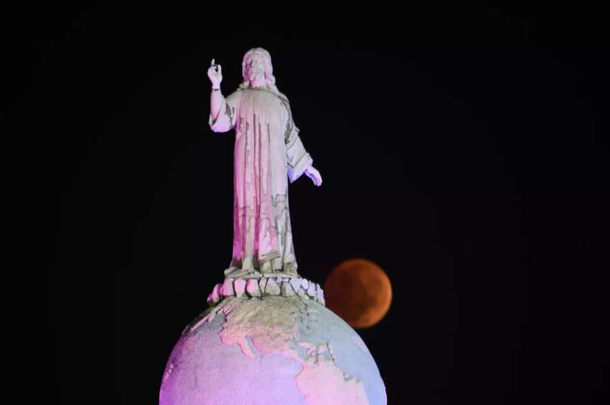 La luna del Castor completamente eclipsada pasa detrás del Monumento al Divino Salvador del Mundo en San Salvador, El Salvador.