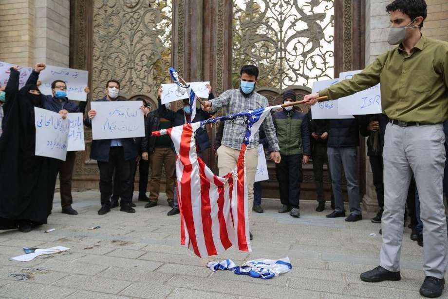 Estudiantes de la fuerza paramilitar Basij de Irán queman banderas estadounidenses e israelíes durante una manifestación en Teherán para protestar por el asesinato del destacado científico nuclear Mohsen Fakhrizadeh.