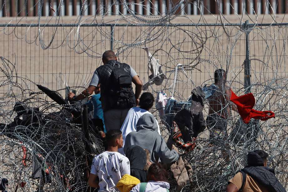 Migrantes cruzan una cerca de alambres en la frontera que divide a México y Estados Unidos, en Ciudad Juárez. 