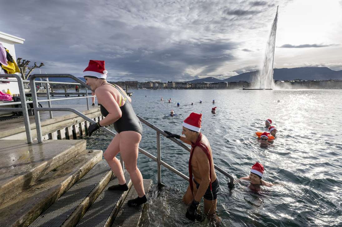 Geneva (Switzerland), 24/12/2022.- Swimming enthusiasts wear Santa hats as they brave the nine degrees Celsius 'warm' water by the famous water fountain 'Le Jet d'Eau' in Lake Leman at the 'Bains des Paquis' in Geneva, Switzerland, on Christmas Eve, 24 December 2022. (Suiza, Ginebra) EFE/EPA/MARTIAL TREZZINI