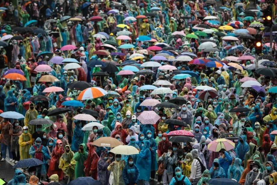 Los manifestantes a favor de la democracia se protegen de la lluvia usando ponchos y paraguas durante una protesta contra el gobierno en el Monumento a la Victoria en Bangkok.