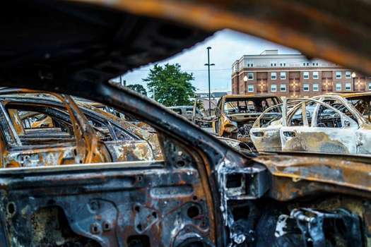 Los restos de autos quemados durante las noches previas de disturbios se ven en un lote de autos usados en Kenosha, Wisconsin.