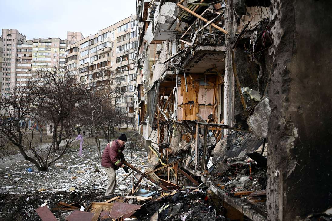 Un hombre limpia los escombros de una zona residencial en la calle Koshytsa, un suburbio de la capital ucraniana que presuntamente fue atacado con un misil ruso, después de que Rusia, bajo el mando de Vladimir Putin, atacara la capital.