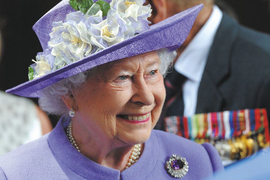 (FILES) In this file photo taken on June 28, 2014 Britain's Queen Elizabeth II smiles as she attends a Solemn Drumhead service at Royal Hospital Chelsea in London. Brightly coloured outfits, a matching hat and a pristine pair of gloves: Queen Elizabeth II's look was instantly recognisable and a self-created uniform styled to suit her role. During her reign, the monarch tried out every shade in the colour chart, from canary yellow to lime green, fuchsia and navy blue. Her inimitable style was developed over the decades by aides and designers, starting with Norman Hartnell, who created her wedding dress when she married Prince Philip in 1947. (Photo by STUART C. WILSON / POOL / AFP)
