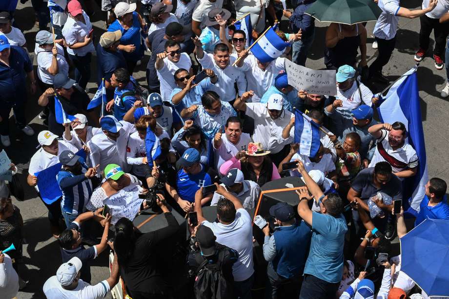 El líder del opositor Partido Nacional, David Chávez (C con gorra y camiseta azul), se une a los manifestantes antigubernamentales en una marcha hacia el palacio presidencial para protestar contra la presidenta hondureña Xiomara Castro, acusándola de intentar establecer el comunismo en el país, en Tegucigalpa el 19 de agosto de 2023.