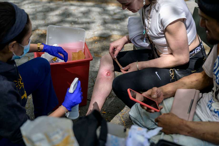 Una enfermera limpia la herida de la consumidora de una drogas en un parque de la ciudad de Nueva York.