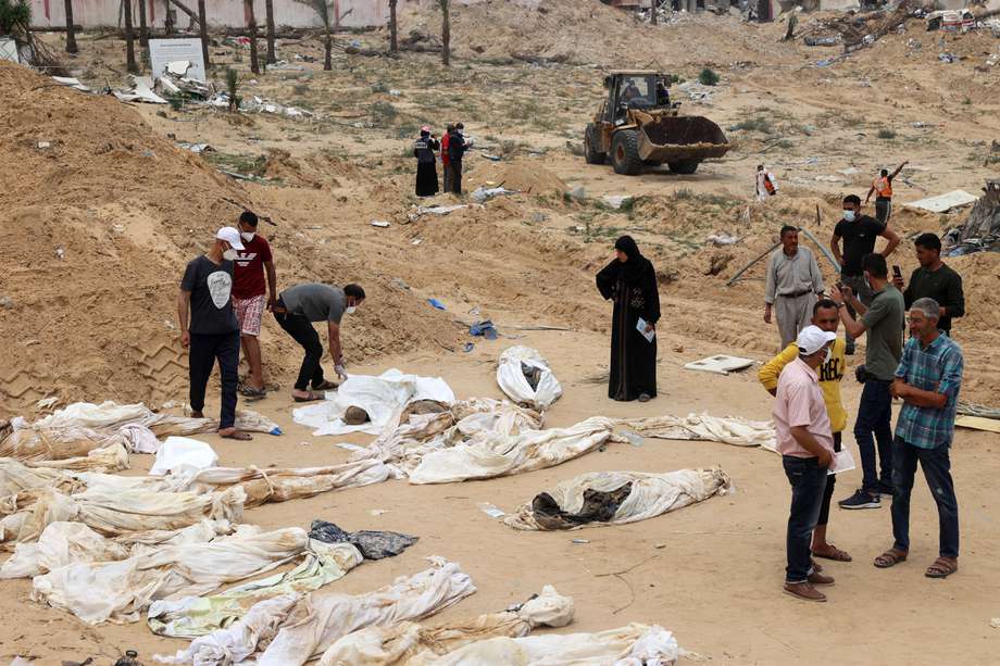 Un grupo se reúne cerca de los cuerpos alineados para su identificación después de que fueron desenterrados de una fosa común encontrada en el Complejo Médico Nasser en el sur de la Franja de Gaza.
