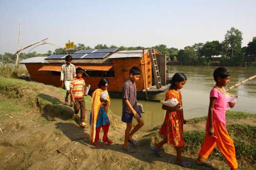 Los niños asisten a una escuela en un barco dirigido por Shidhulai Swanirvar Sangstha, una ONG fundada en 1998 con la misión de ayudar a las comunidades que viven a lo largo de los vastos humedales de Chalan Beel en el distrito de Rajshahi. Al construir una flota de botes de fondo plano que funcionan con energía solar, todos fabricados con materiales disponibles localmente, Shidhulai ofrece una variedad de instalaciones de educación, salud y capacitación a las familias que viven junto al agua.