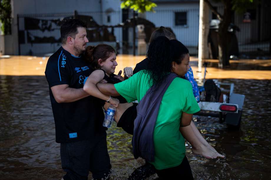 Pobladores del barrio Farrapos reciben ayuda para evacuar sus viviendas tras la crecida del lago Guaíba este lunes en Porto Alegre (Brasil). 