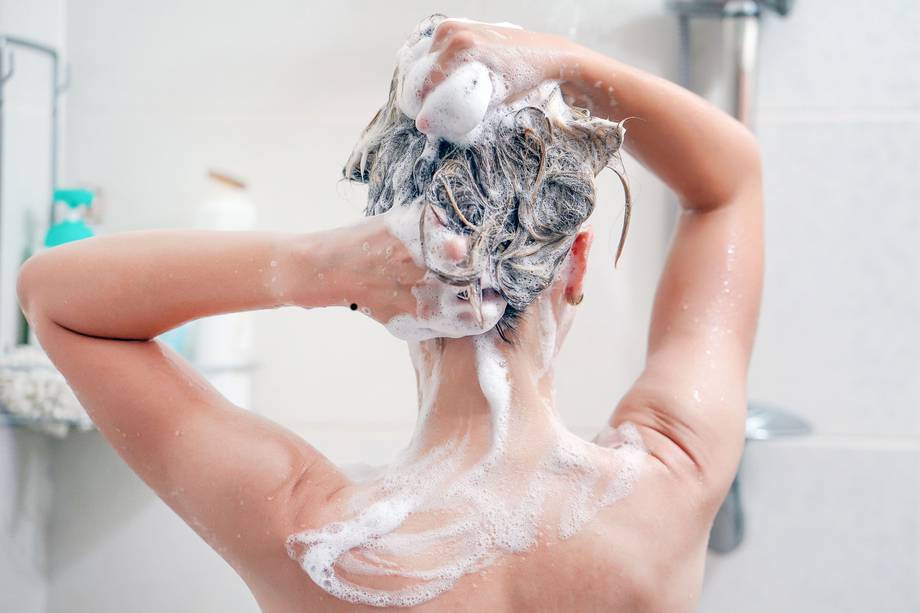 Una mujer lavando su pelo en la ducha.