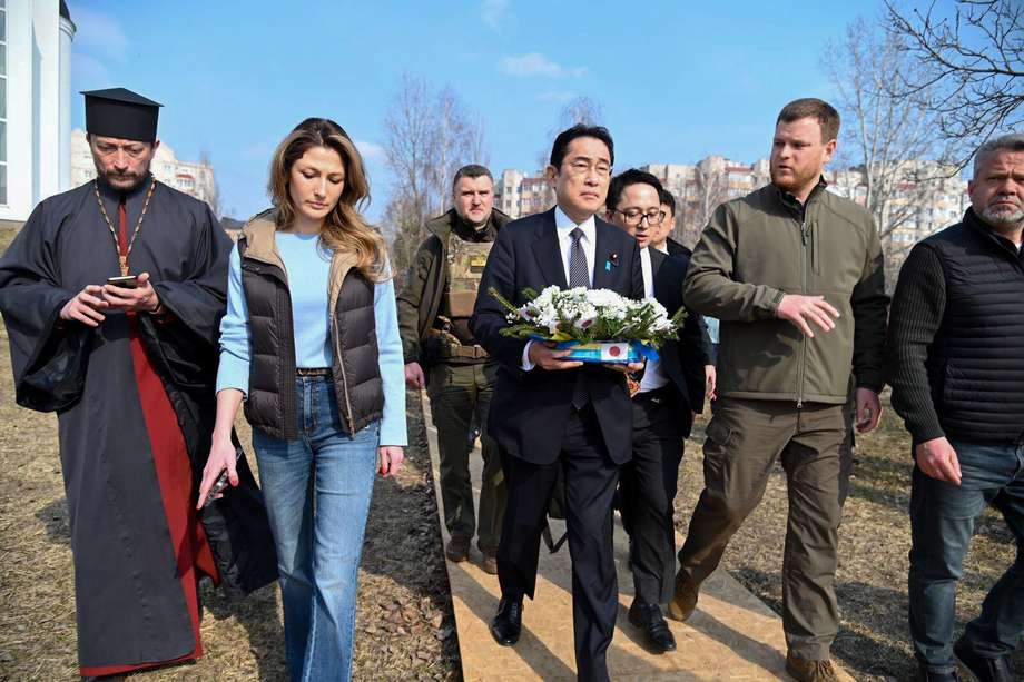 El primer ministro japonés Fumio Kishida (C) mientras deposita flores en una fosa común en Bucha, Ucrania, el 21 de marzo de 2022. Kishida está en una visita de un día a Ucrania.