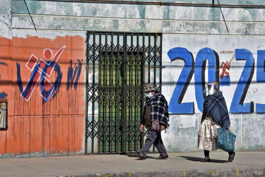 Women walk past a graffiti with political propaganda of former Bolivian President Evo Morales, in El Alto, Bolivia on September 26, 2020.  General elections will take place in Bolivia on October 18 amid the new coronavirus pandemic.  / AFP / AIZAR RALDES
