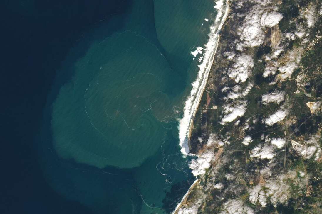 El Landsat 8 captó un impresionante despliegue de la inmensa fuerza de olas de siete pisos de altura cuando se estrellaban contra la costa cerca de Nazaré, un punto caliente de surf de olas en Portugal. La imagen muestra cómo las feroces olas desgarraban el sedimento del fondo marino circundante formando enormes penachos submarinos que se extendían a unos 10 km de la costa.
La imagen fue tomada el mismo día en que un surfista de 18 años rompió una ola récord de 30,9 m en Nazaré.