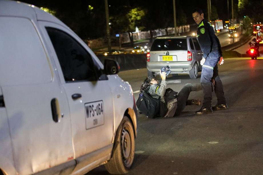 Momento de la agresión que termina con el periodista de El Espectador en el suelo en plena vía pública con vehículos en tránsito.