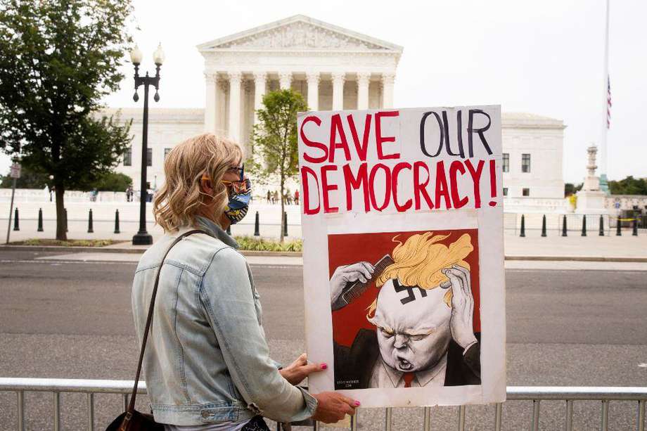 Una mujer frente a la Corte Suprema con una pancarta en la que crítica a Donald Trump.
