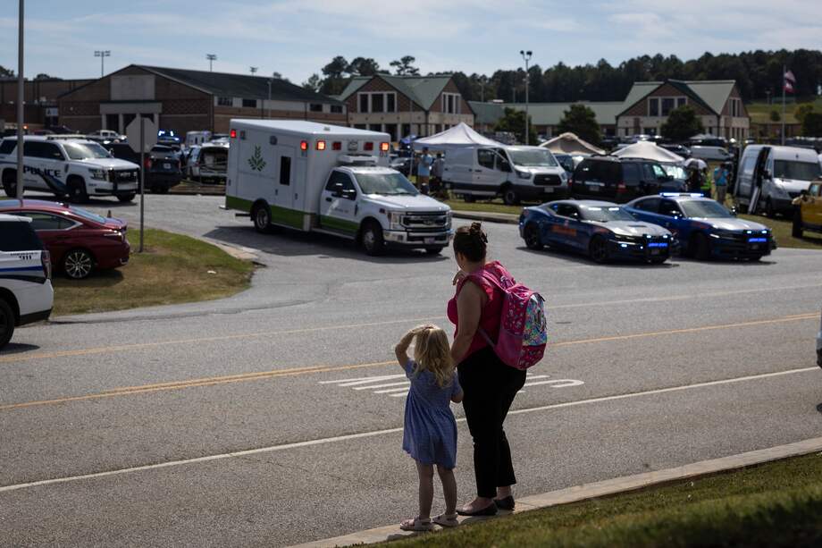 Una niña y su madre observan cómo las fuerzas del orden y los socorristas rodean la escuela secundaria Apalachee, en Winder, Georgia, tras un tiroteo.