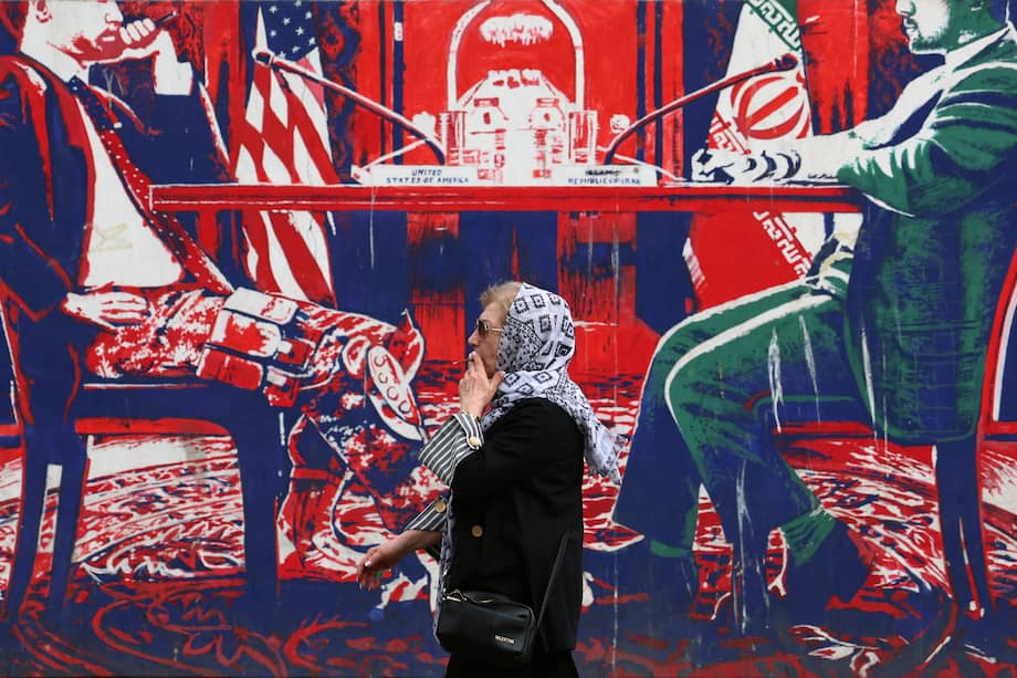 Una mujer iraní fuma mientras camina junto a un mural antiestadounidense, junto a la antigua embajada de Estados Unidos en Teherán, Irán, el 7 de abril de 2025.