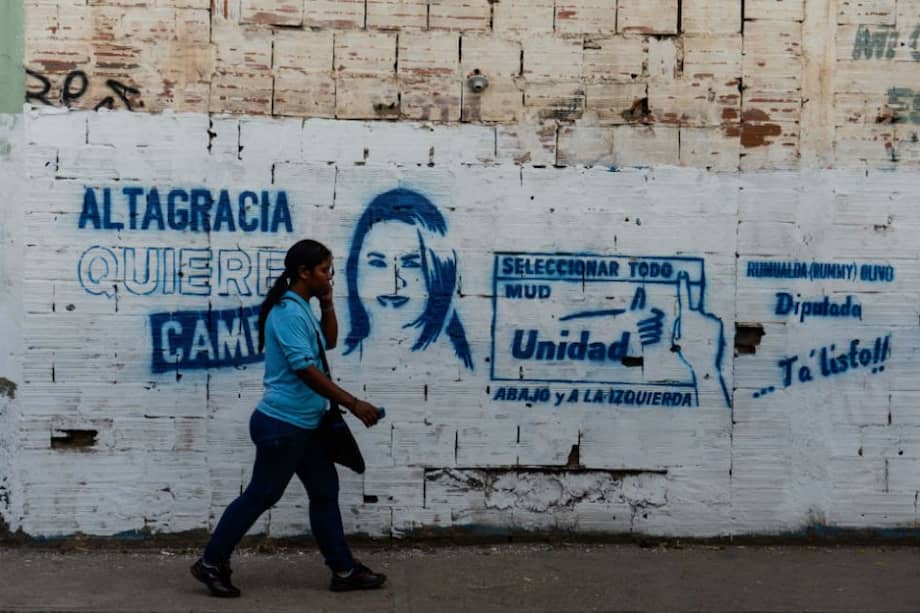Una mujer camina en inmediaciones a un mural que representa a un candidato de la oposición venezolana para las próximas elecciones legislativas en la ciudad de Altagracia de Orituco, en el estado Guárico Venezuela. /AFP