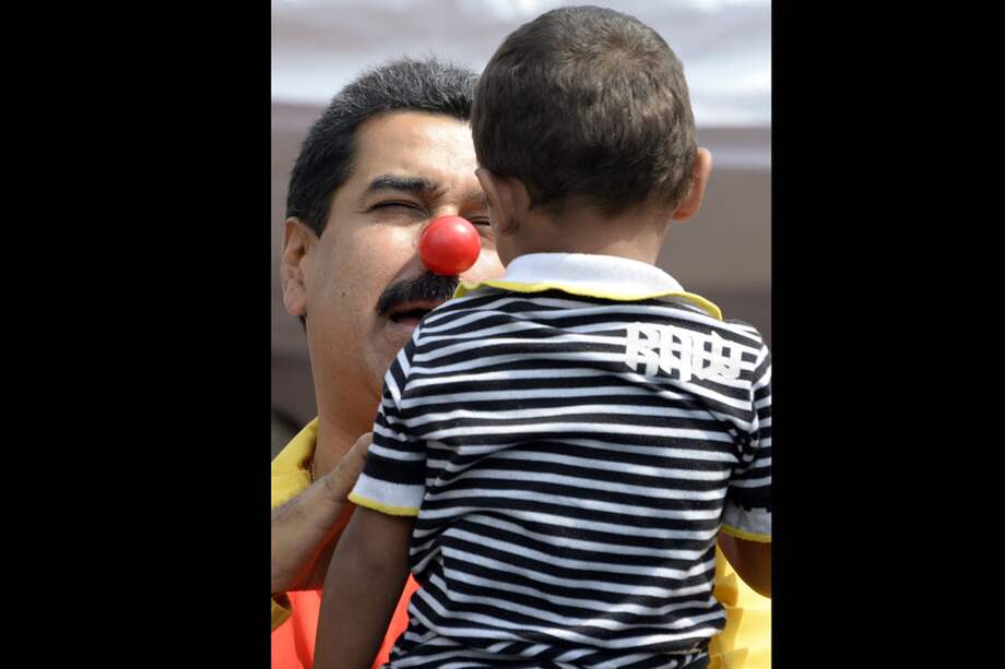 El presidente de Venezuela, Nicolás Maduro, juega con un niño durante un acto público en Caracas. / AFP
